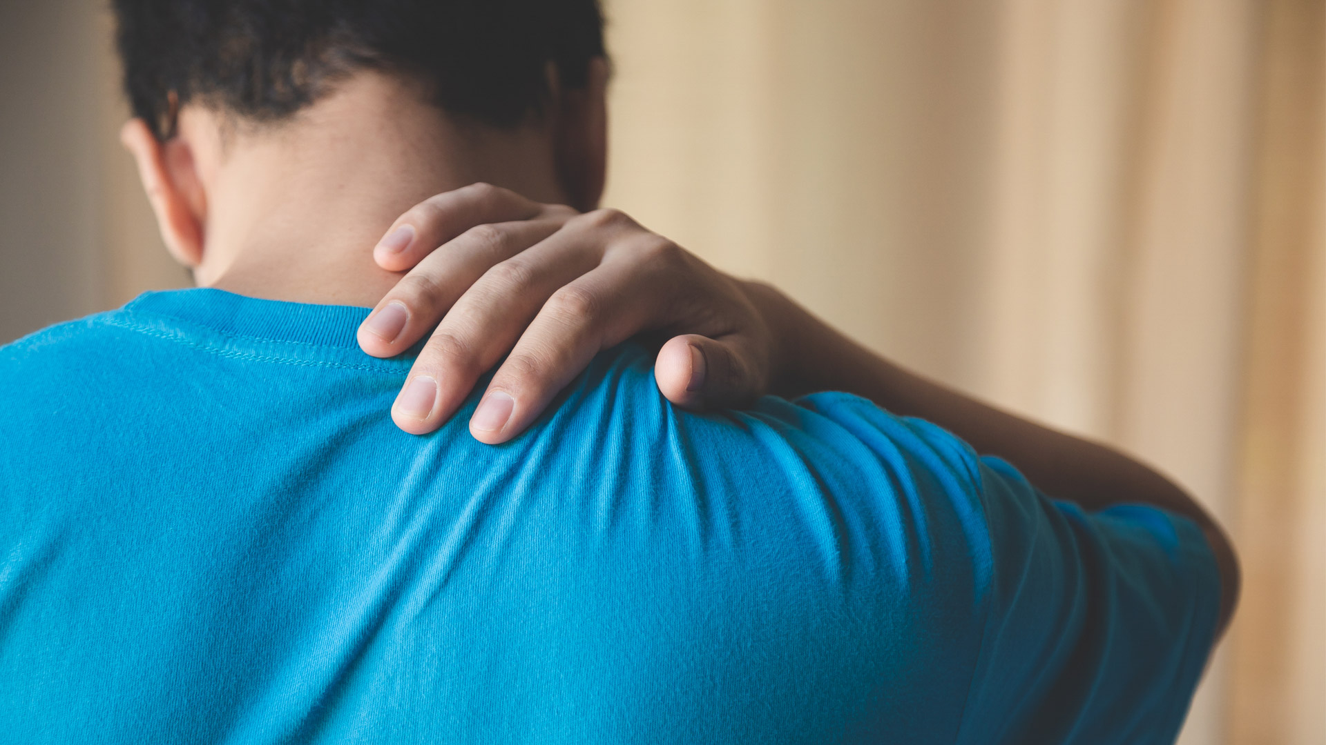Man with neck pain holding his neck at his car accident chiropractor office.